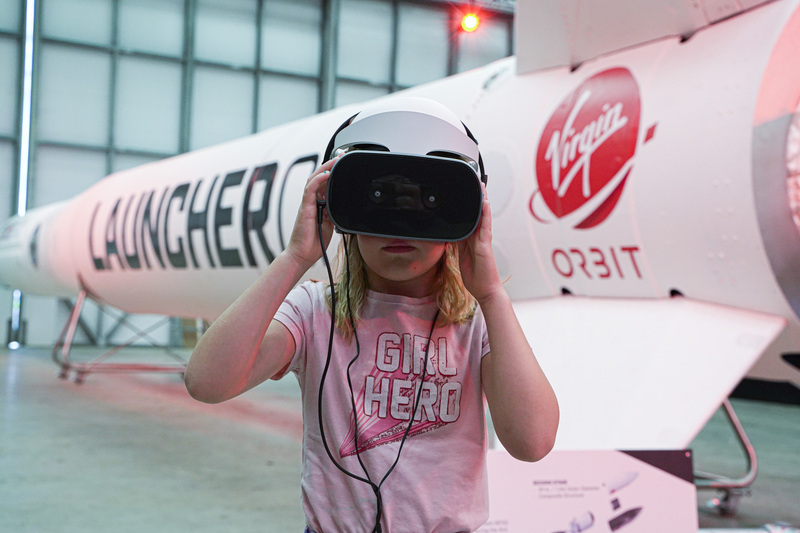 Girl wearing a VR headset while standing in front of a rocket